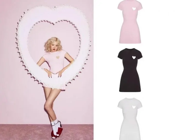 Model posing inside a pink heart-shaped frame next to three short dresses in pink, black and white
