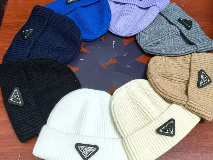 Ribbed knit beanies in cream, black, grey and blue with small triangular logo patches